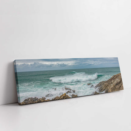 Breaking wave on the rocky Cornish coast. Panoramic Canvas picture print.