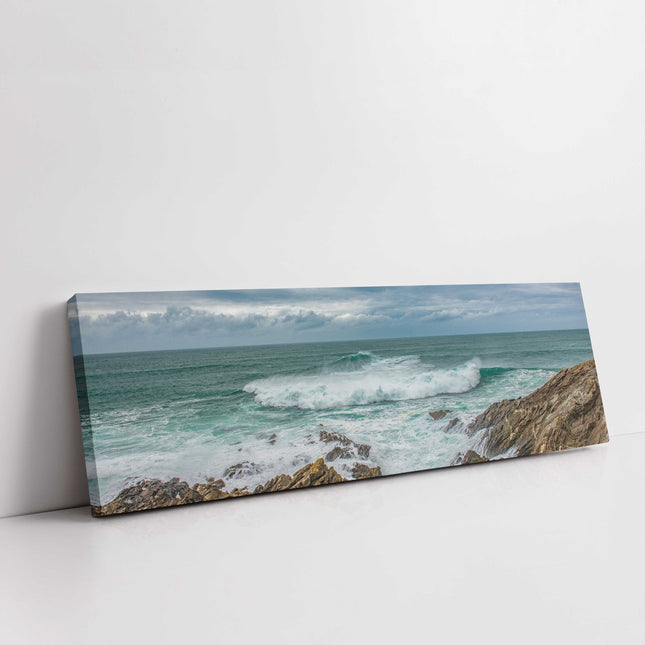 Breaking wave on the rocky Cornish coast. Panoramic Canvas picture print.